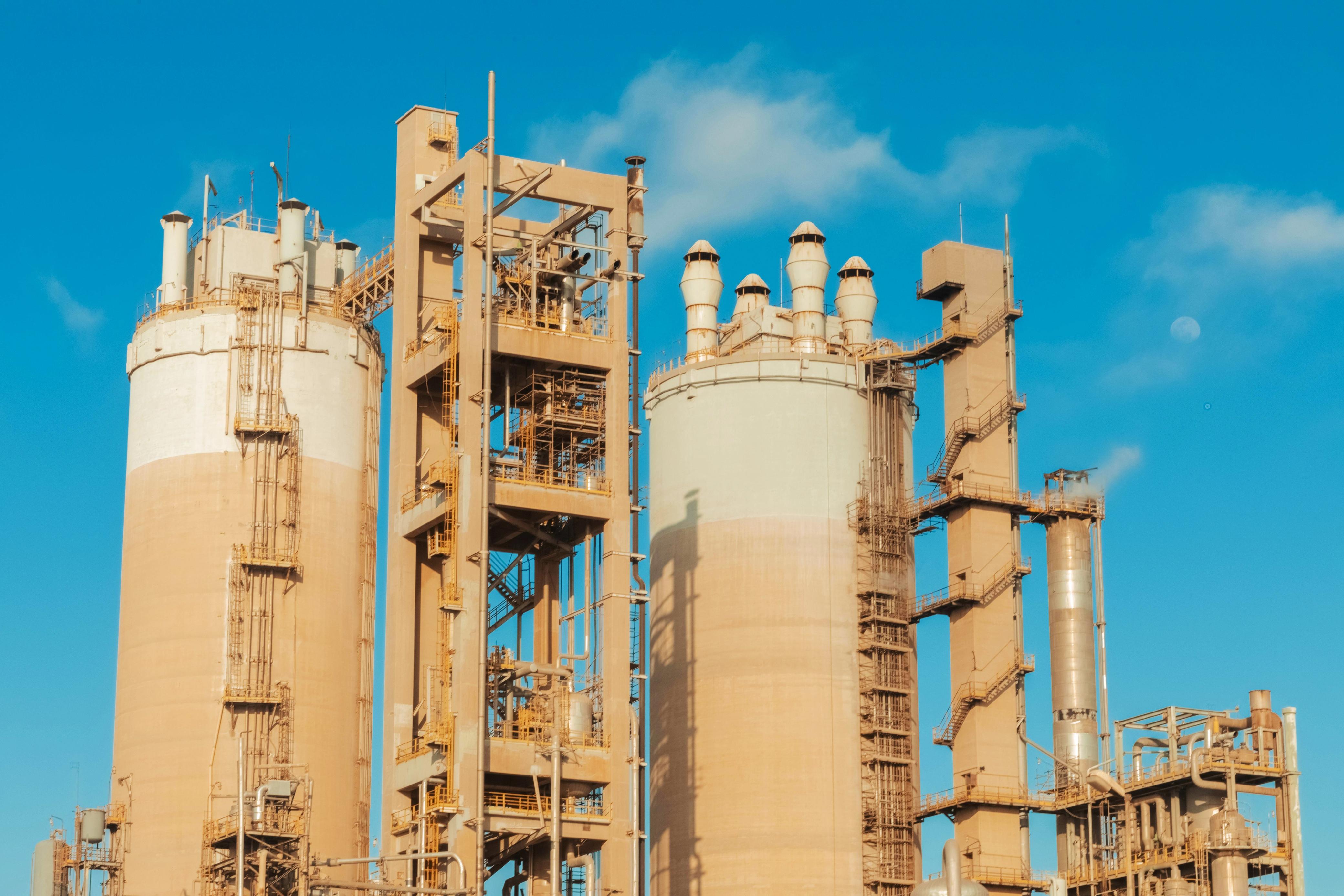 Wide shot of a massive oil refinery facility with industrial steel structures and pipelines